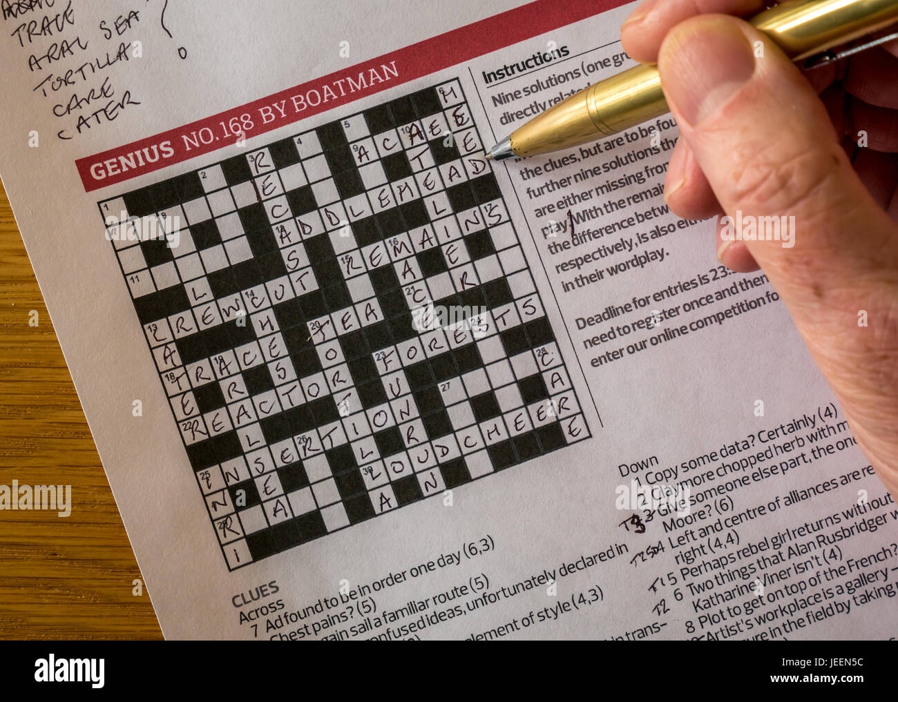 Solving Complicated Crossword Puzzle In The Guardian Newspaper Called Genius By Crossword Setter Nom De Plume Boatman With Man s Hand Holding Pen Stock Photo Alamy